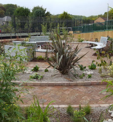 An image of a landscaping job we did with a small round flower bed and seating area