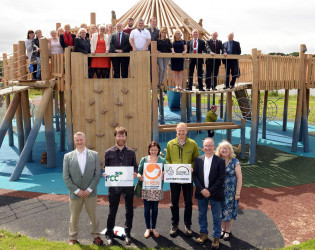 An image of a large play area we created with a huge custom jungle gym, we have the whole team and everyone involved with it standing in front of it