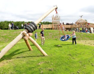 Child playing on a swing being pushed by another person